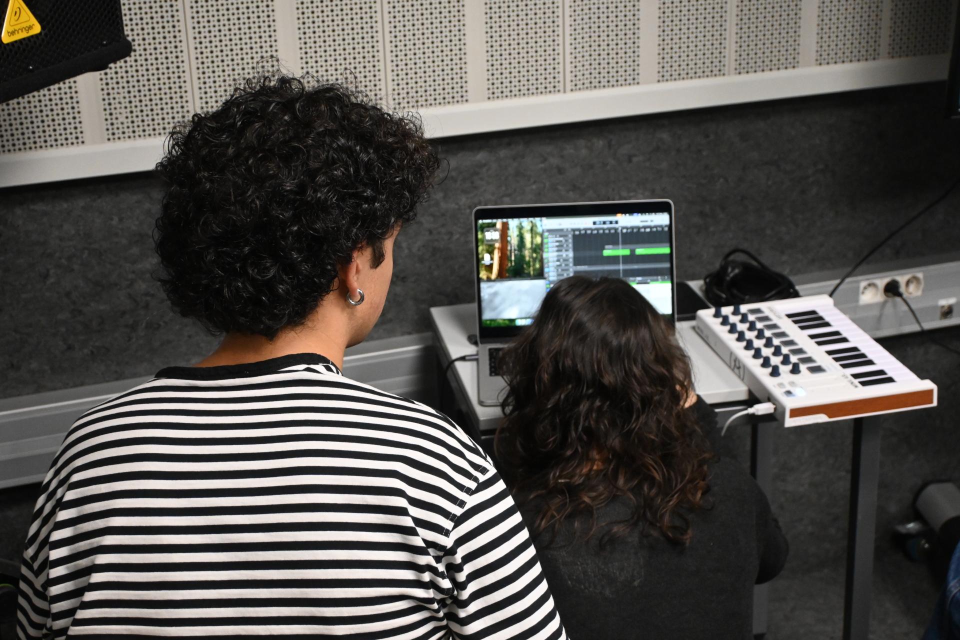 Dos membres del tercer grup, mentre componen amb el programari integrat al portàtil.
