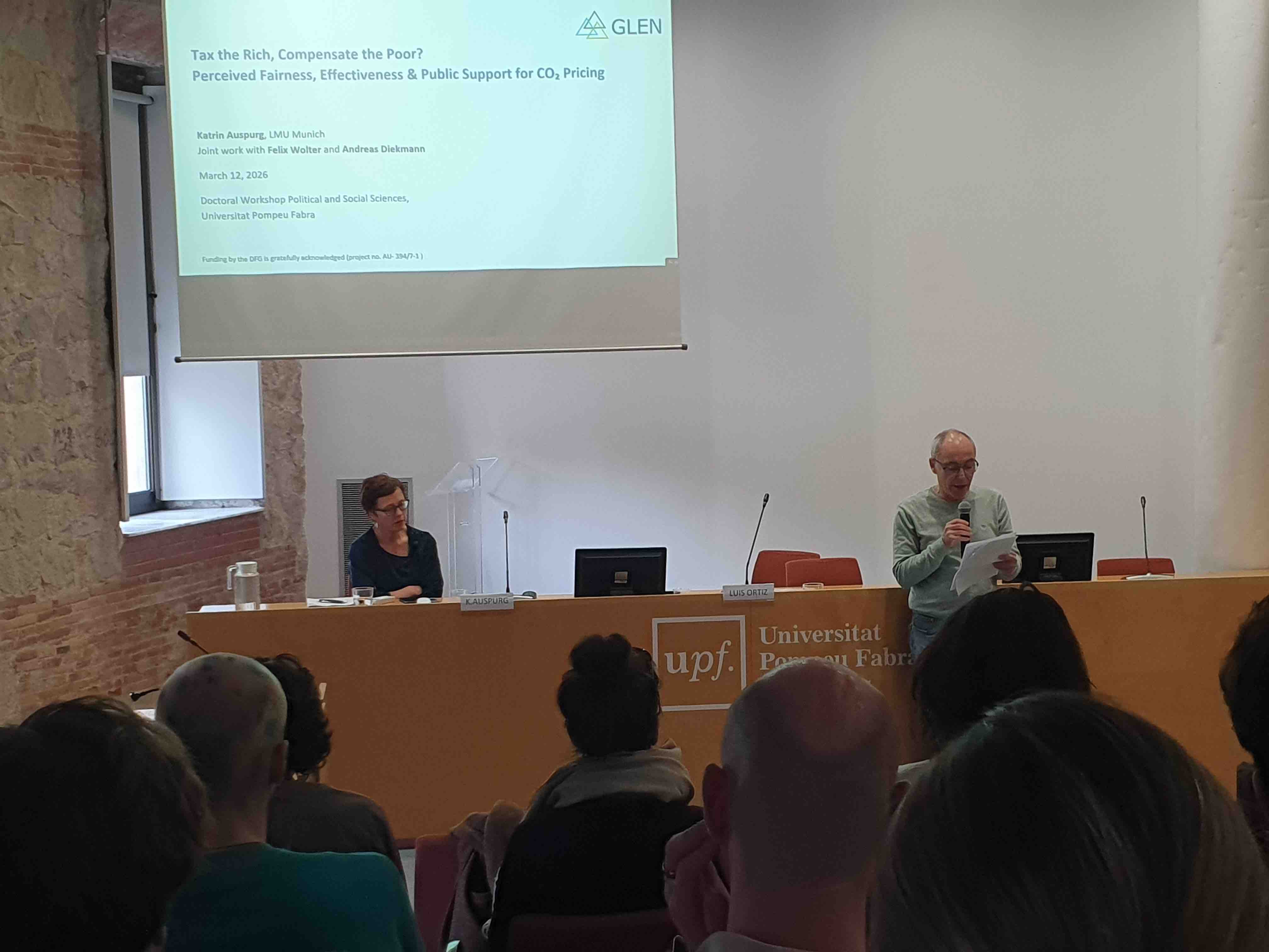 Katrin Auspurg (left) being presented by Jorge Rodríguez before giving the closing lecture in front of the audience in Sala de Graus Albert Calsamiglia (12/03/2026).